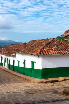 Vertical view of a street corner with green and white colonial buildings in Barichara, Colombia
