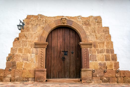Wooden door on a colonial building with a stone arch in Barichara, Colombia