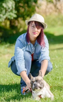 beautiful young woman with her dog french bulldog in the park