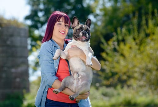 beautiful young woman with her dog french bulldog in the park