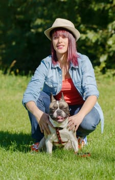 beautiful young woman with her dog french bulldog in the park
