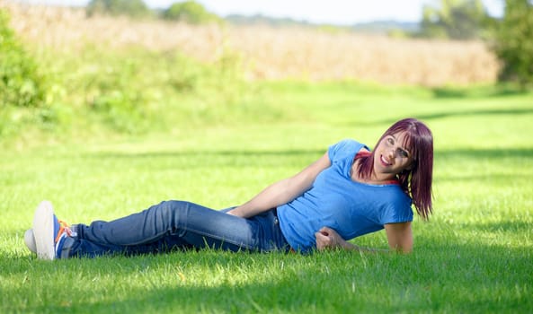 beautiful young woman in jeans lying on the grass, in park