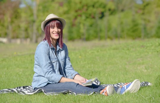 beautiful young woman sitting in the grass in the countryside