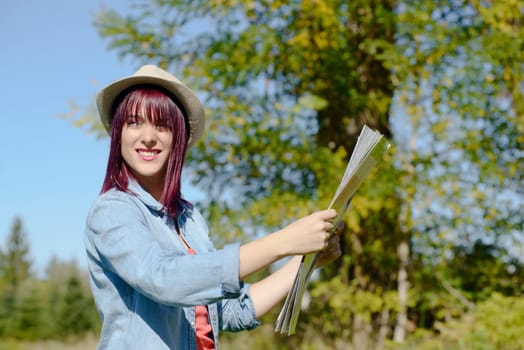 beautiful young woman with hat and map in the countryside