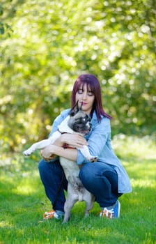 beautiful young woman with her dog french bulldog in the park