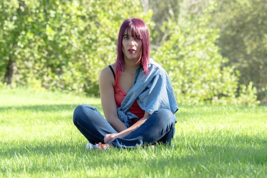 beautiful young woman with red hairs sitting in the grass in the countryside