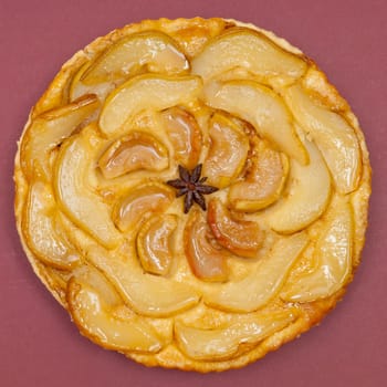 Whole tarte Tatin apple and pear tart pie isolated on claret background with copy space
