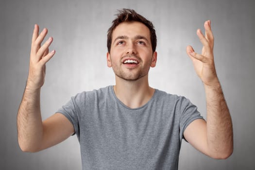 Young man looking up and worship God with raised hands