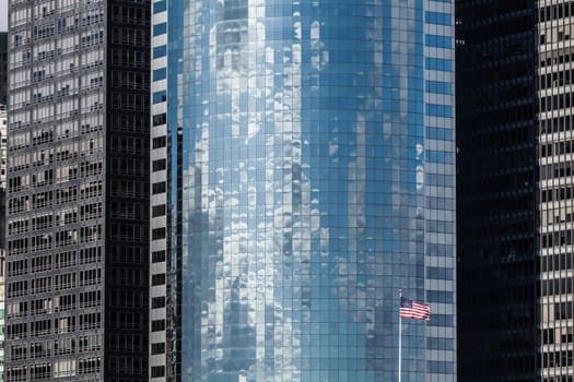 Modern skyscraper background and US flag in Manhattan, New York City.