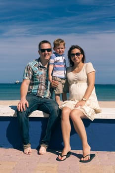 Happy pregnant couple and their son enjoying sunny day on the coast in Spain.