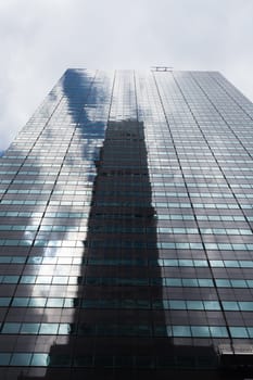 Low angle view of a skyscraper with glass windows and reflections in Manhattan, New York City.