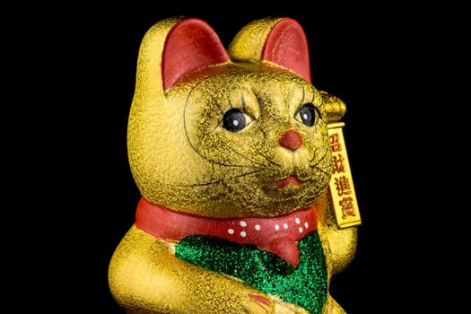 Waving cat,gold-plated welcome cat with waving paw against a black background