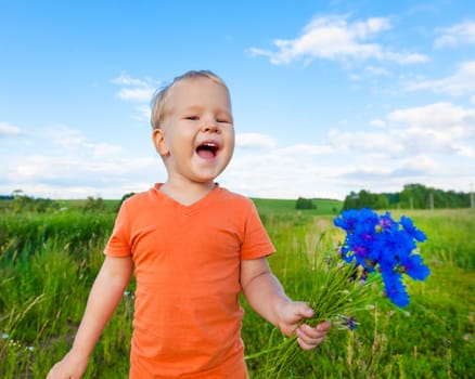 Adorable boy with cornflowers outdoor laughing