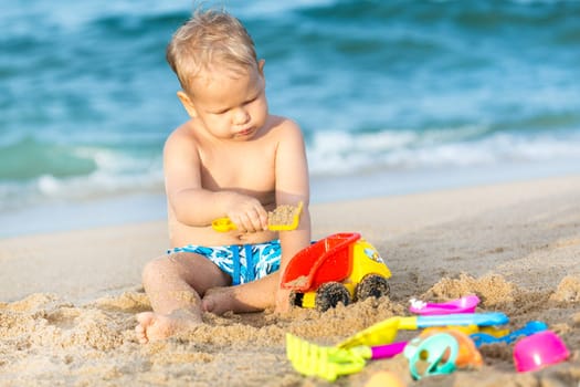 Cute boy on the tropical beach playing toys