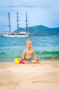 Cute boy on the tropical beach playing toys