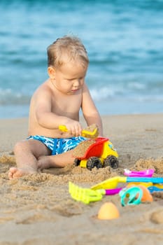 Cute boy on the tropical beach playing toys