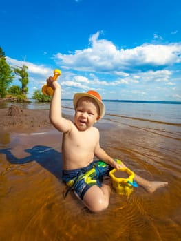 Cute boy on the riverside playing toys