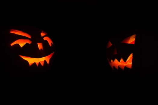 halloween pumpkins with candles inside on black background