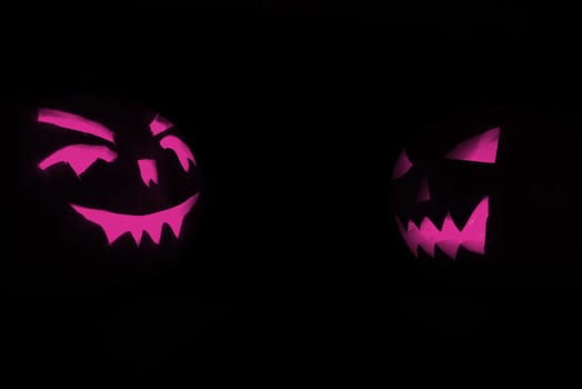 two purple halloween pumpkins on black background
