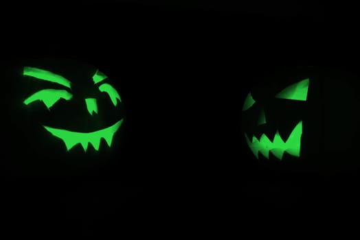 two green halloween pumpkins on black background