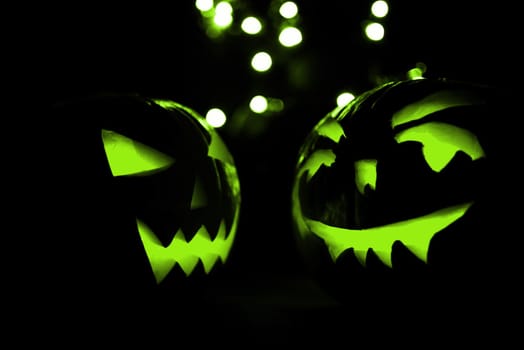 two halloween pumpkins with green bokeh light on black background