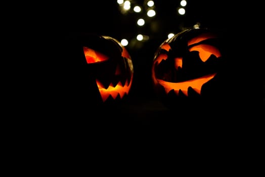two halloween pumpkins with bokeh light on black background