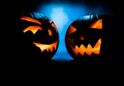 two scary halloween pumpkins on a blue light background.