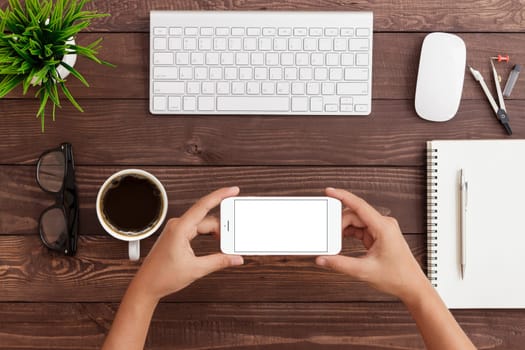 hand holding phone horizontal showing phone blank screen on work table, mock up phone rose gold color