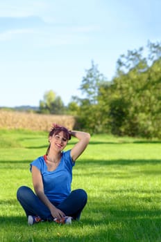 beautiful young woman sitting in the grass in the countryside