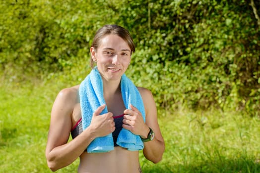 portrait of young sporty woman with blue towel in the countryside