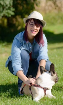 beautiful young woman with her dog french bulldog in the park