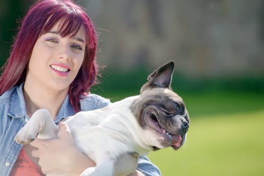 beautiful young woman with her dog french bulldog in the park