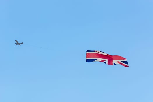 Banner tow,small powered aircraft with tow banner for advertising.. Here is the flag of Great Britain..