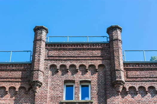 House façade of a typical old brick house in front of a blue sky..