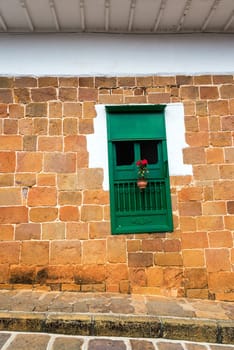 Green window with red flowers in a beautiful colonial building in Barichara, Colombia