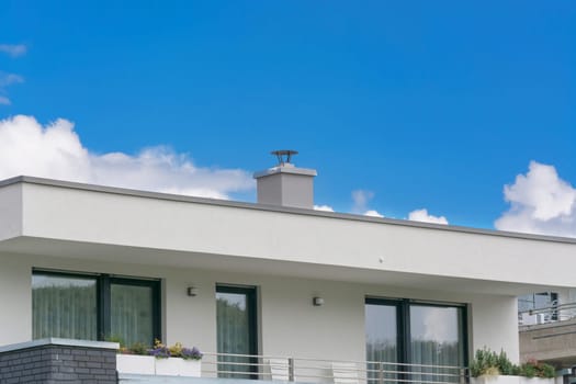 Upper floor of a modern residential building in bungalow style with flat roof in front of blue sky..
