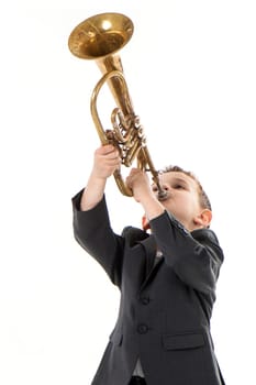 young boy blowing into a trumpet against white background