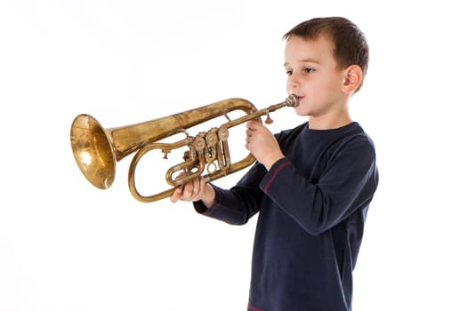 young boy blowing into a trumpet against white background