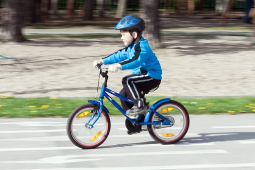 child on a bicycle at asphalt road on traffic playground - blurred panning method
