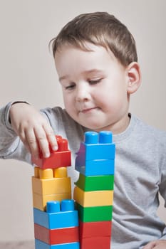 Playing little boy with colored cubes