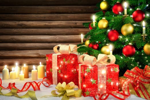 Shiny Christmas scene with a Christmas tree,candles,ornamental gift boxes with lamps,bows,snow and a rustic wooden wall background