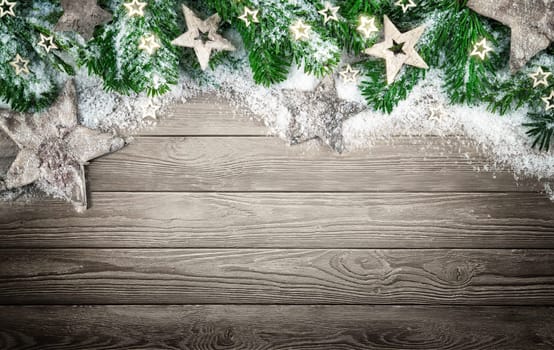 Christmas background in natural,elegant and simple wood style,with a border of fir branches,wooden stars and snow