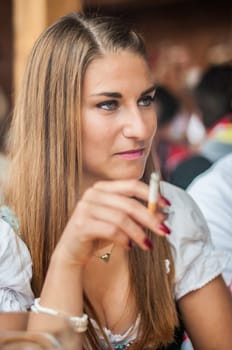 Young lovely woman  in Dirndl or tracht dress sitting and smoking at the Oktoberfest