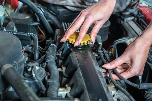 Young female car mechanic in auto repair service, red automobile, long fingernail