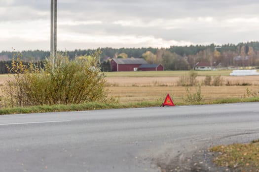 Warning Triangle on Road with field in the background.