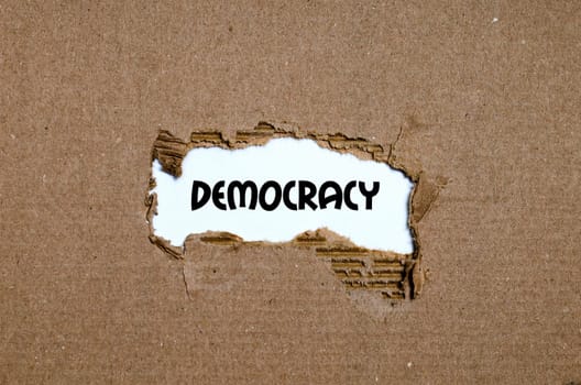 The word democracy appearing behind torn paper