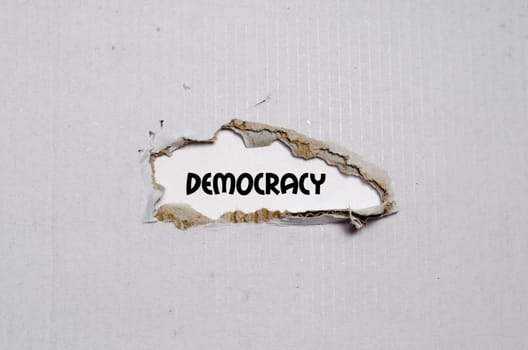 The word democracy appearing behind torn paper