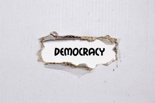 The word democracy appearing behind torn paper