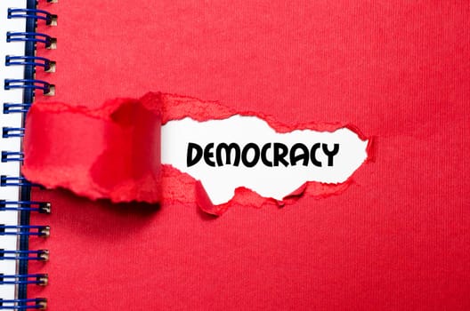 The word democracy appearing behind torn paper