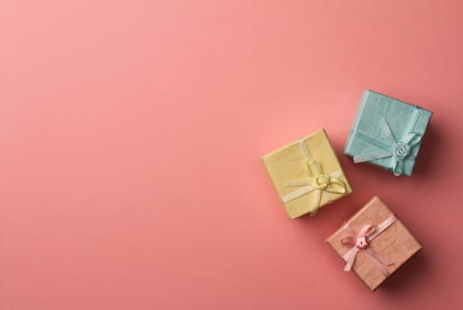 Top view of three small cardboard rectangular gift boxes on red paper background with copy space